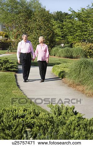 Stock Image - Mature couple walking down sidewalk. Fotosearch