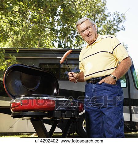 Senior adult man grilling hotdogs with RV in background. View Large Photo Image Stock Image - Senior adult man grilling hotdogs with RV in background.. Fotosearch