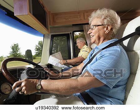 Senior adult woman driving RV and smiling while man reads map in passenger seat. View Large Photo Image Stock Image - Senior adult woman driving RV and smiling while man reads map in passenger seat.. Fotosearch