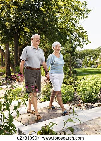 Senior Caucasian couple holding hands and walking outdoors in park. View Large Photo Image Stock Photo - Senior Caucasian couple holding hands and walking outdoors in park.. Fotosearch
