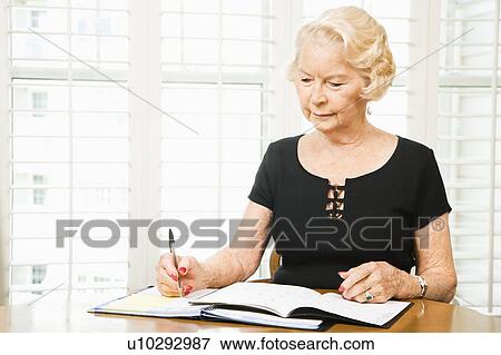 Stock Photo - Woman writing in her planner.. Fotosearch