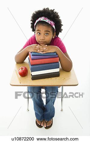 African American girl sitting at school desk with large stack of books looking up at viewer. View Large Photo Image Stock Image - African American girl sitting at school desk with large stack of books looking up at viewer.. Fotosearch