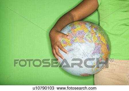 Stock Image - Arm of African American girl holding globe at hip.. Fotosearch