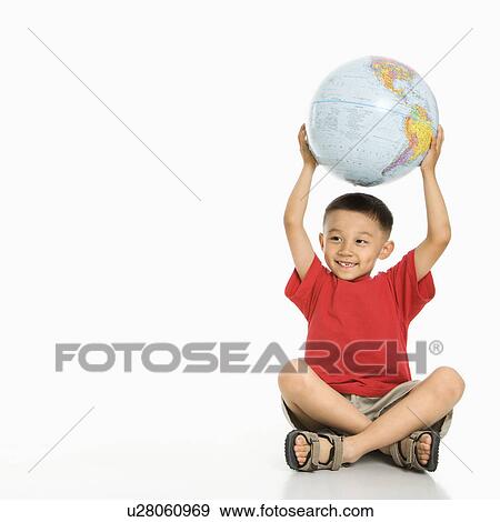 Boy sitting on floor holding Earth globe over his head View Large Photo Image Stock Photo - Boy sitting on floor holding Earth globe over his head. Fotosearch