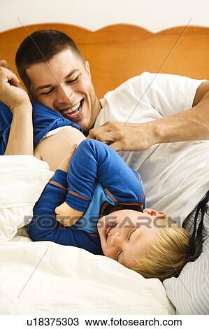 Caucasian toddler boy and father playing and tickling in bed. View Large Photo Image Stock Image - Caucasian toddler boy and father playing and tickling in bed.. Fotosearch