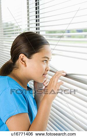 Stock Photograph - Girl looking through blinds out window. Fotosearch