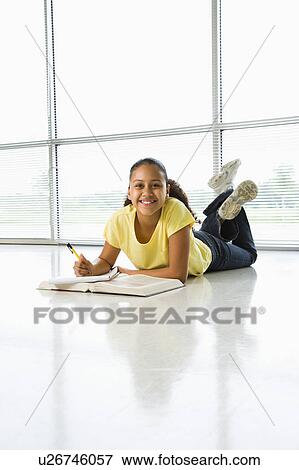 Stock Photo - Girl lying on floor doing homework . Fotosearch