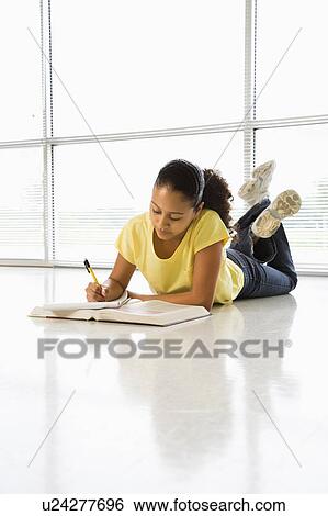 Girl lying on floor doing schoolwork View Large Photo Image Stock Photograph - Girl lying on floor doing schoolwork. Fotosearch