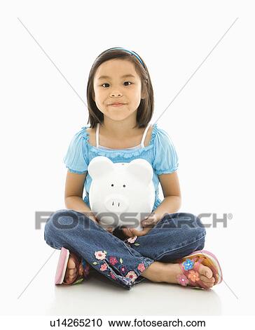 Stock Image - Girl sitting on floor holding piggybank. Fotosearch