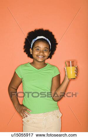 Stock Photo - Girl with hand on hip holding glass of orange juice. Fotosearch