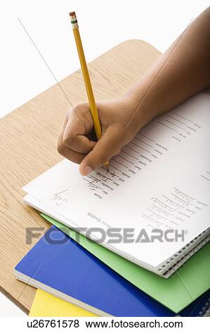 Stock Photo - Hand of girl at school desk writing in notebook with pencil. Fotosearch