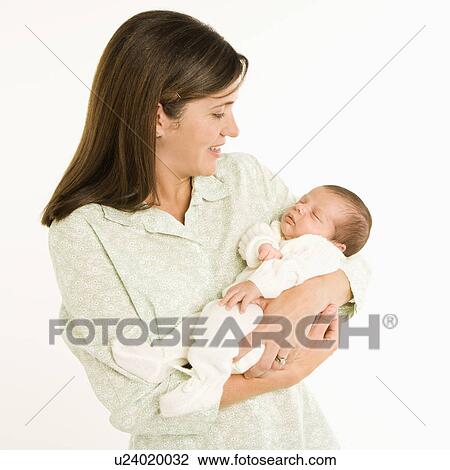 Stock Image - Mother holding baby smiling against white background.. Fotosearch