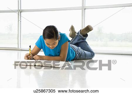 Stock Photography - Preteen girl laying on floor doing homework. Fotosearch