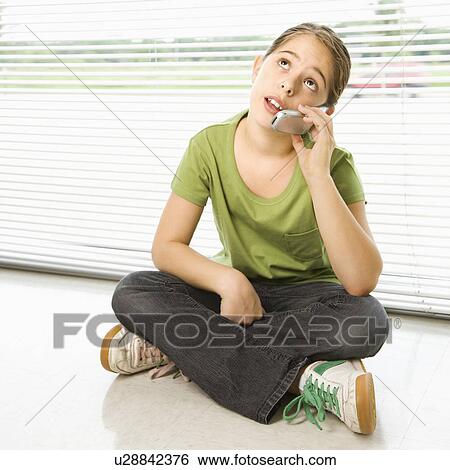 Stock Photograph - Preteen girl sitting on floor talking on cell phone. Fotosearch