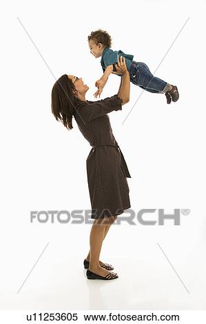 Stock Photography - Side view of a mom lifting happy toddler son into air above head. Fotosearch
