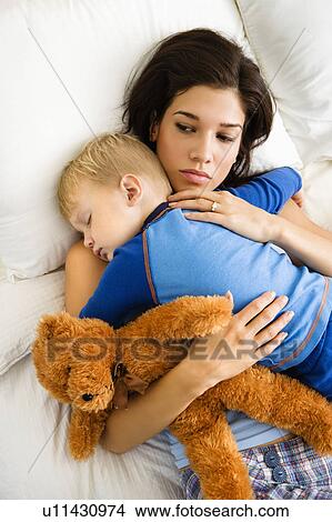 Picture - Woman holding sleeping toddler in bed . Fotosearch
