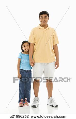 Stock Image - Asian father standing holding hands with daughter.. Fotosearch