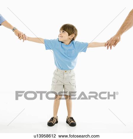 Stock Image - Boy holding hands with parents standing against white background.. Fotosearch