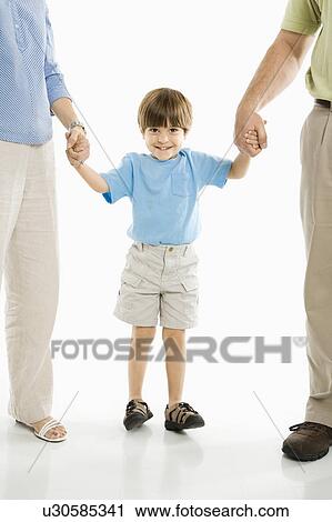Boy holding hands with parents standing against white background View Large Photo Image Stock Image - Boy holding hands with parents standing against white background. Fotosearch