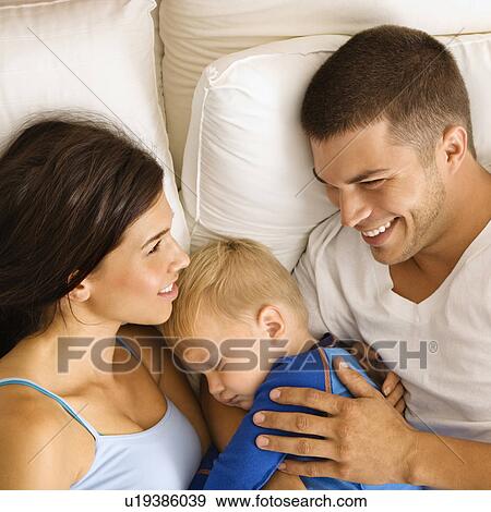 Stock Photo - Caucasian mid adult parents with toddler son sleeping in bed. . Fotosearch