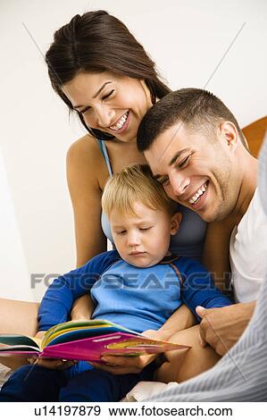 Stock Photo - Caucasian parents and toddler son reading book.. Fotosearch