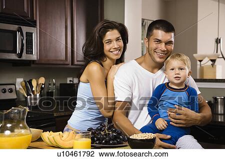 Stock Image - Family with toddler son in kitchen at breakfast smiling at viewer. Fotosearch