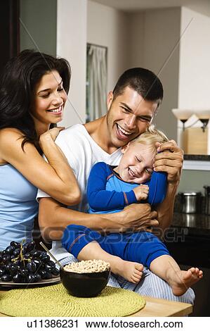 Family with toddler son in kitchen at breakfast smiling and tickling View Large Photo Image Stock Image - Family with toddler son in kitchen at breakfast smiling and tickling. Fotosearch