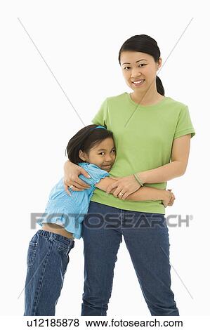Stock Photo - Mother and daughter standing with arms around each other. Fotosearch