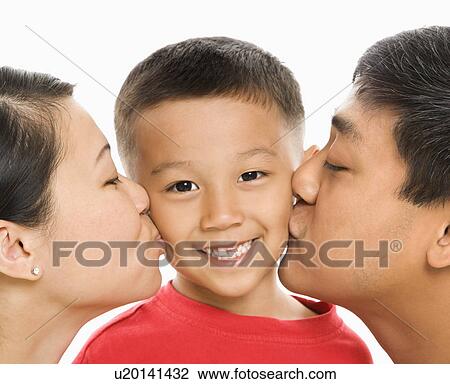 Stock Image - Mother and father kissing opposite cheeks of smiling son. Fotosearch