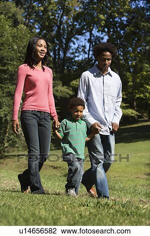 Parents and young son walking in park holding hands View Large Photo Image Stock Image - Parents and young son walking in park holding hands. Fotosearch