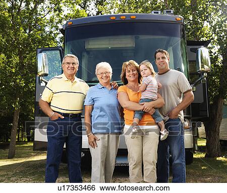 Stock Photograph - Portrait of three generation family standing in front of recreational vehicle smiling and looking at viewer. Fotosearch