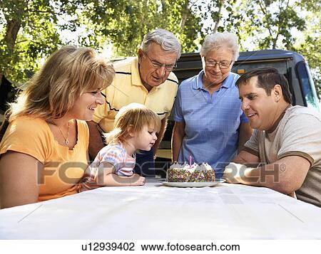 Three generation Caucasian family seated at picnic table celebrating female childs birthday with cake. View Large Photo Image Stock Image - Three generation Caucasian family seated at picnic table celebrating female childs birthday with cake.. Fotosearch