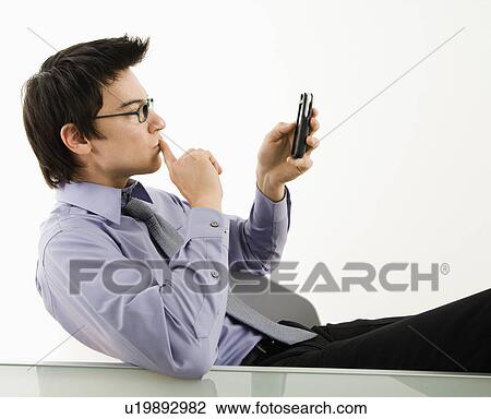 Businessman sitting at desk texting using his pda cellphone View Large Photo Image Stock Image - Businessman sitting at desk texting using his pda cellphone. Fotosearch