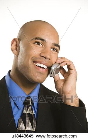Stock Photography - Head and shoulder portrait of African American man in suit talking on cellphone.. Fotosearch
