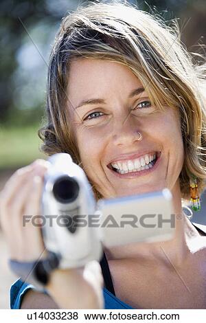Mid-adult Caucasian woman outdoors pointing video camera at viewer. View Large Photo Image Stock Photo - Mid-adult Caucasian woman outdoors pointing video camera at viewer.. Fotosearch