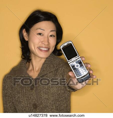 Pretty mid adult Asian woman holding out cell phone. View Large Photo Image Stock Photo - Pretty mid adult Asian woman holding out cell phone.. Fotosearch