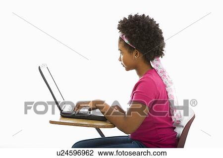Side view of African American girl sitting in school desk typing on laptop computer. View Large Photo Image Stock Image - Side view of African American girl sitting in school desk typing on laptop computer.. Fotosearch
