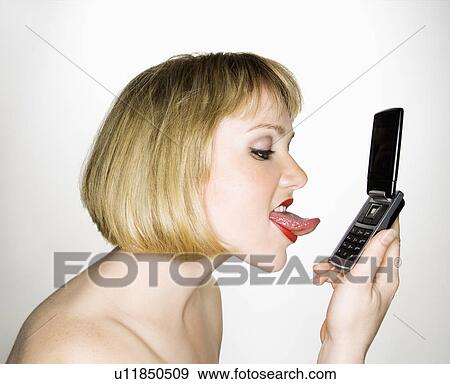 Stock Photo - Side view of young blonde caucasian woman who is about to lick her cell phone.. Fotosearch