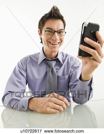 Stock Photo - Smiling Asian businessman with his pda cellphone.. Fotosearch
