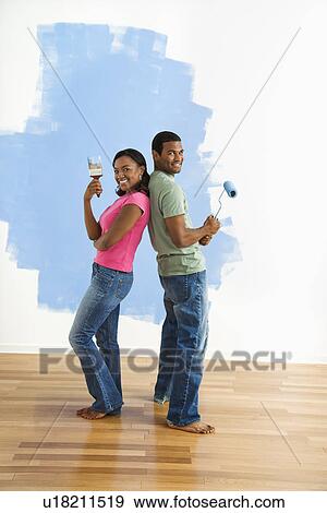 African American couple next to half-painted wall as they stand back to back with paint utensils. View Large Photo Image Stock Photo - African American couple next to half-painted wall as they stand back to back with paint utensils.. Fotosearch