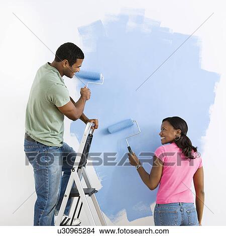 African American male and female couple painting wall blue and smiling at each other. View Large Photo Image Picture - African American male and female couple painting wall blue and smiling at each other.. Fotosearch