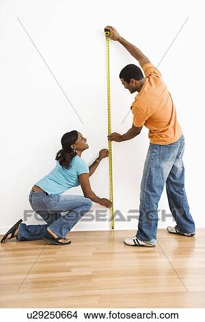African American male and female measuring wall. View Large Photo Image Picture - African American male and female measuring wall.. Fotosearch