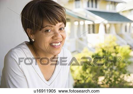 Stock Photography - African American middle aged woman smiling at viewer outside home.. Fotosearch