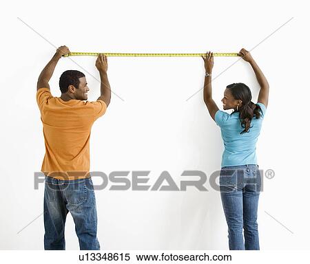 Stock Photography - Male and female measuring wall. Fotosearch