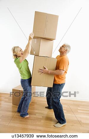 Man holding stack of cardboard moving boxes while woman places another one on View Large Photo Image Stock Photo - Man holding stack of cardboard moving boxes while woman places another one on. Fotosearch