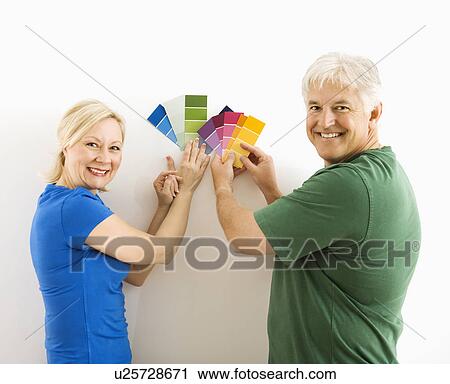 Middle-aged couple holding up and comparing paint swatches. View Large Photo Image Stock Image - Middle-aged couple holding up and comparing paint swatches.. Fotosearch
