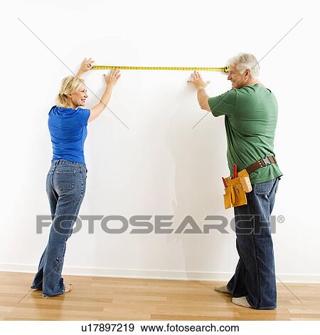 Middle-aged couple measuring wall with tape. View Large Photo Image Stock Photo - Middle-aged couple measuring wall with tape.. Fotosearch