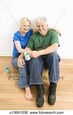Middle-aged couple sitting on floor together drinking coffee. View Large Photo Image Stock Photo - Middle-aged couple sitting on floor together drinking coffee.. Fotosearch