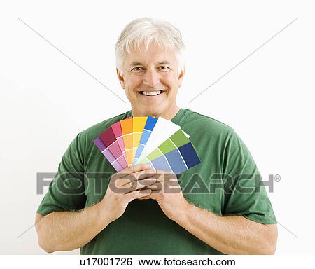 Stock Photograph - Middle-aged man holding up paint swatches.. Fotosearch