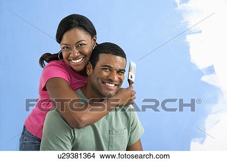Picture - Portrait of African American male and female couple next to half-painted wall.. Fotosearch